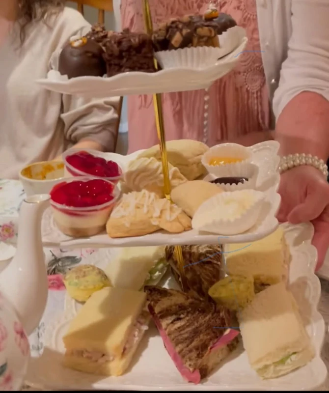 Woman holding a 3 tier dessert tray with an array of sweet treats