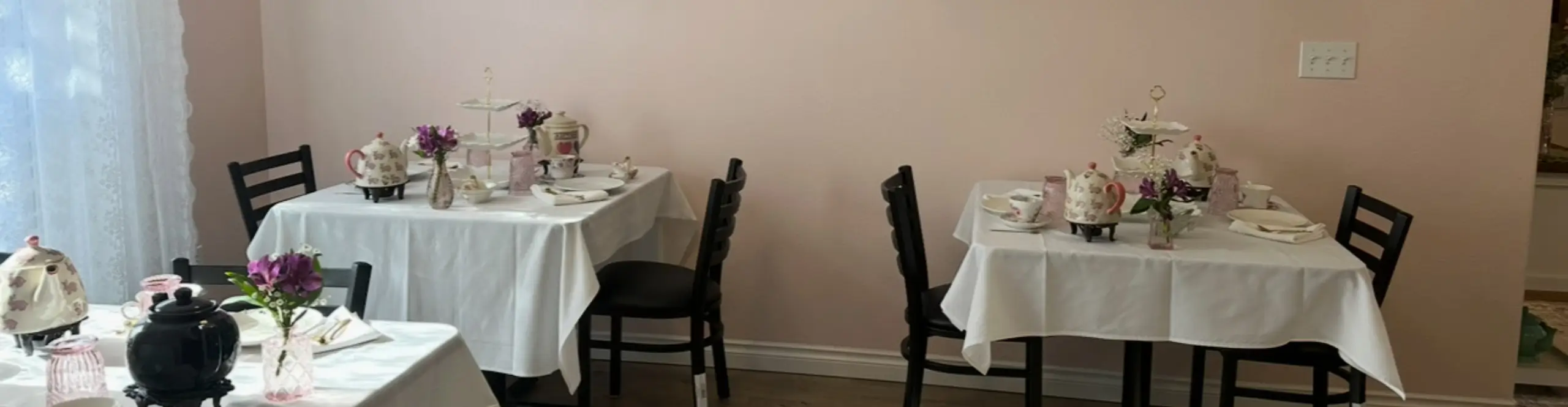Several tables set up with tea pots, cups, flowers and silverware | Honey Bunny’s Tea House