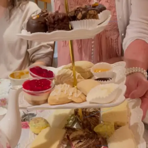 Woman holding a 3 tier dessert tray with an array of sweet treats | Honey Bunny’s Tea House
